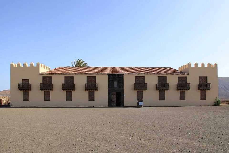 The long whitewashed two-storey facade of the Casa de los Coroneles in La Oliva, with wooden balconies and corner towers, Fuerteventura