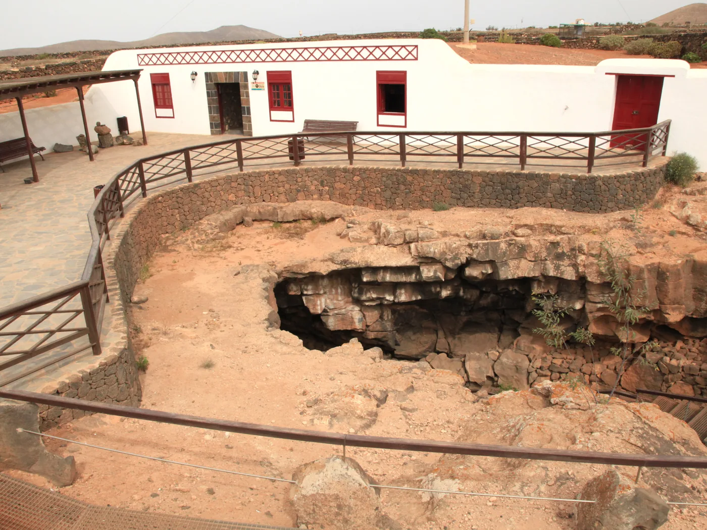 The collapsed volcanic sinkhole entrance to Cueva del Llano, with the visitor centre building behind, near Villaverde
