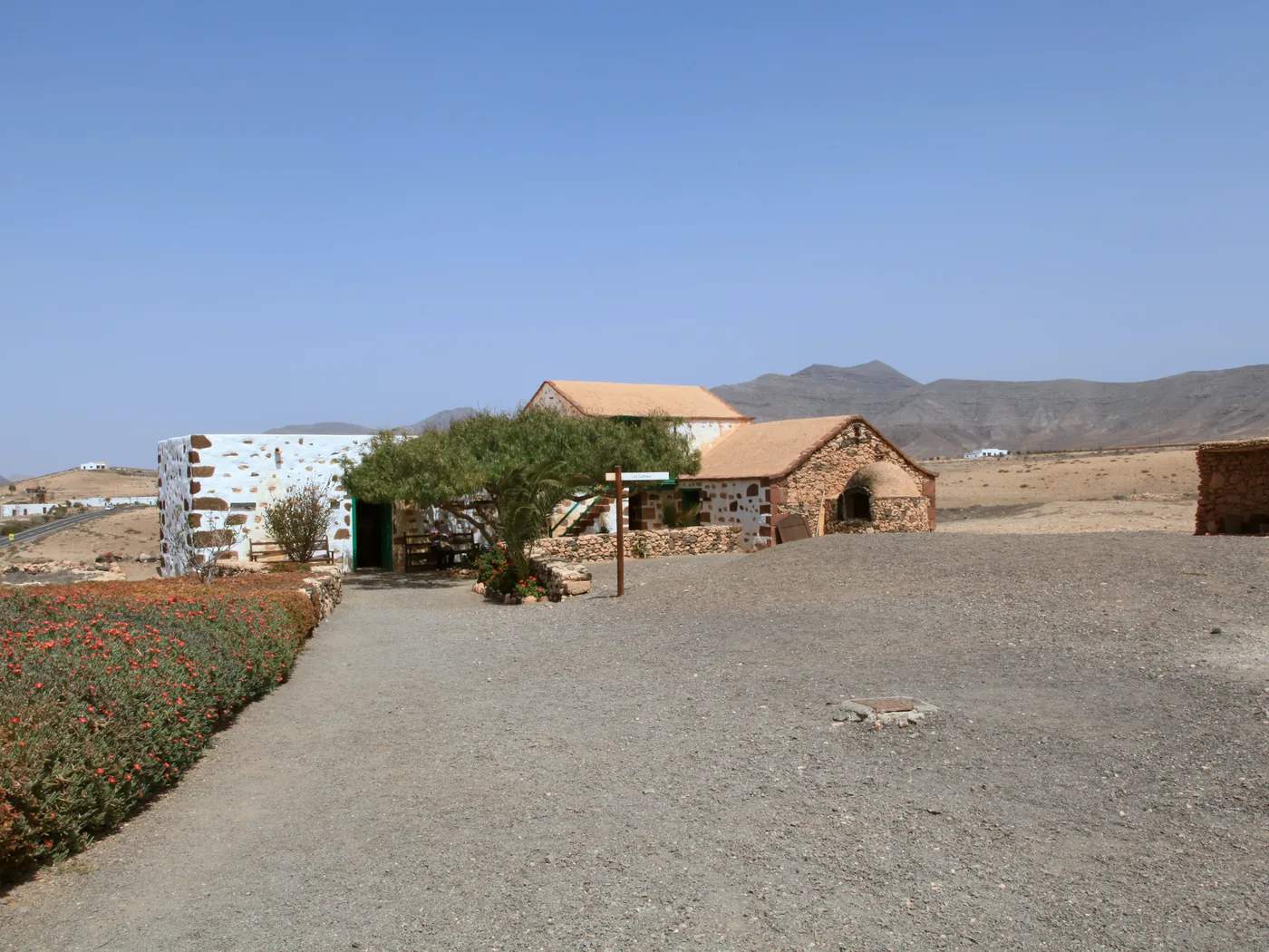 Restored traditional stone farmhouses with mountains behind at Ecomuseo La Alcogida, Tefía