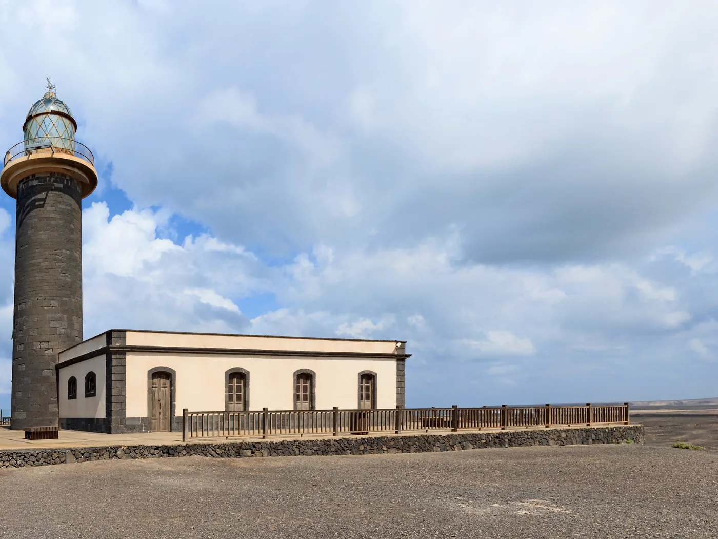 The lighthouse and keeper's building at Punta de Jandía under a cloudy sky at Fuerteventura's remote southern tip