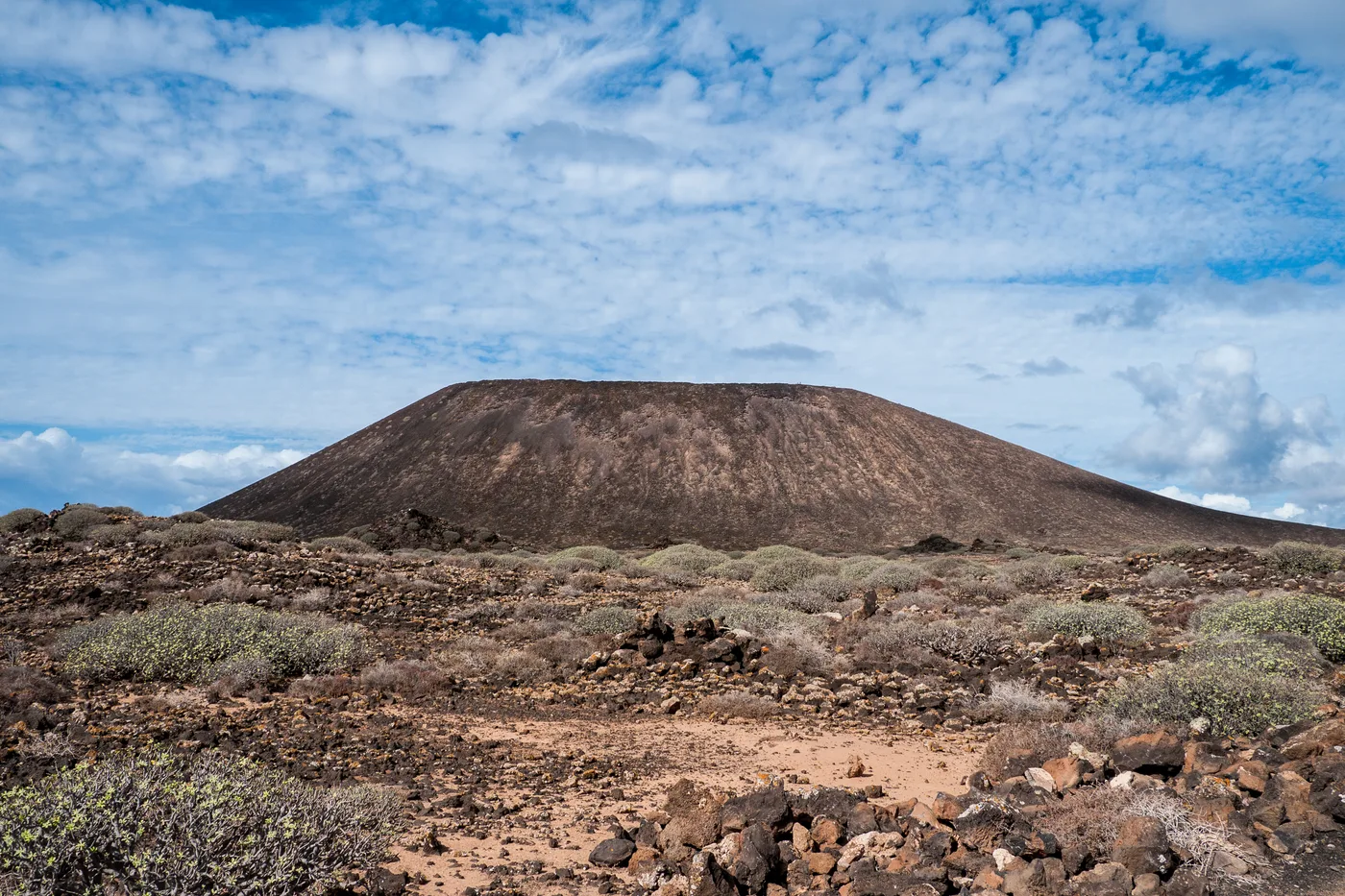 The volcanic cone of Montaña de la Caldera rising above scrubland and lava rock on Isla de Lobos