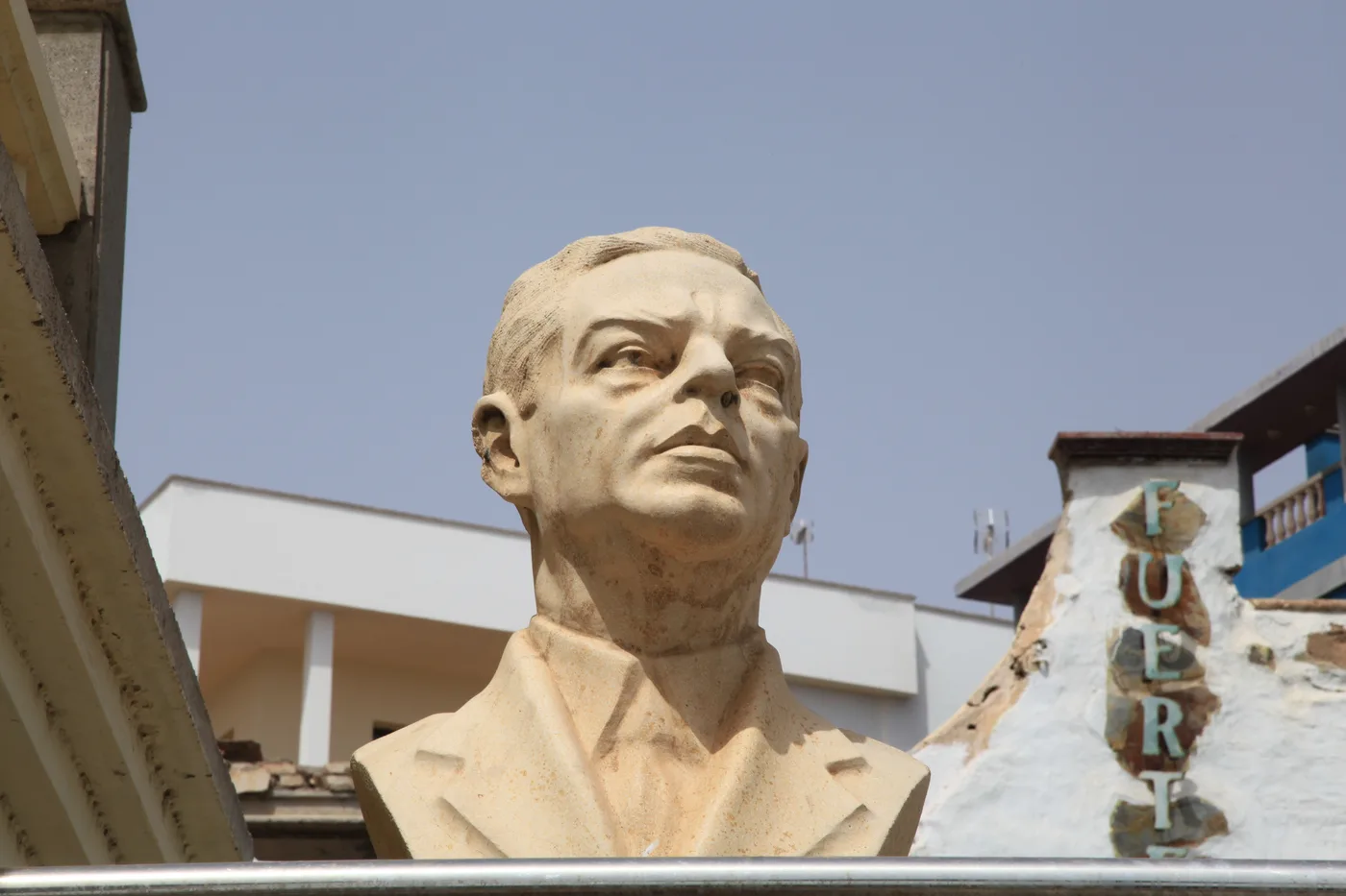 A weathered stone bust sculpture along Puerto del Rosario's Avenida de los Reyes de España, part of the city's open-air sculpture route