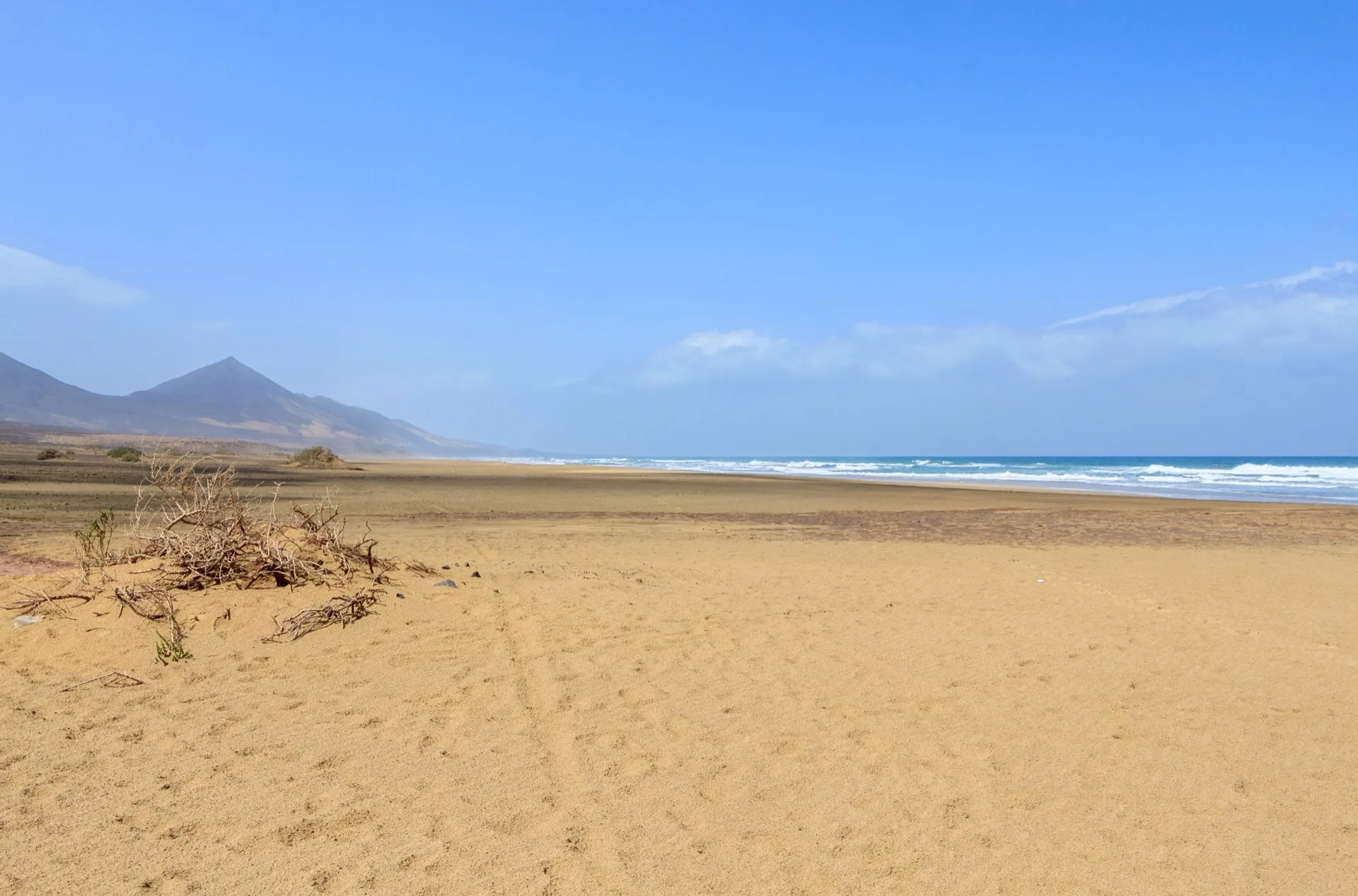 Wild waves breaking on the empty beach of Cofete with the Jandía mountains behind