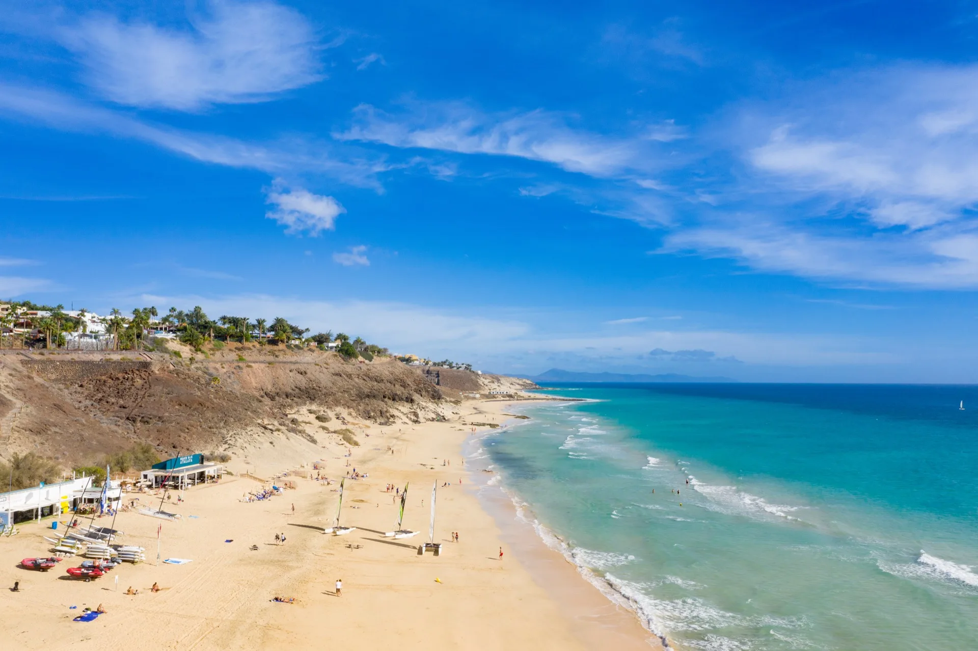 Golden sand of Playa de Esquinzo with calm Atlantic water and low cliffs on the Jandía coast