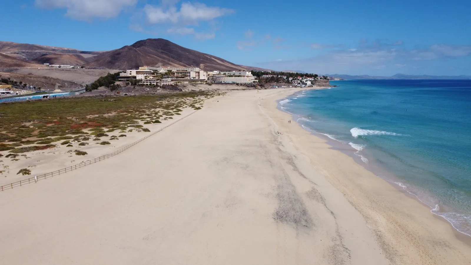 Long curve of Playa del Matorral beach below the white houses of Morro Jable on Fuerteventura's southern coast